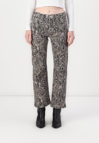 Pantalons à motif peau de serpent dans des teintes de gris et de noir, avec une taille ajustée et des jambes évasées, associés à des bottines noires.