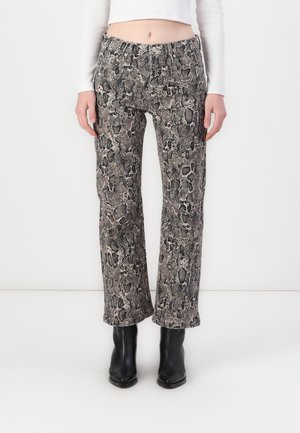 Snakeskin-patterned trousers in shades of gray and black, featuring a fitted waist and flared legs, paired with black ankle boots.