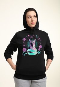Felpa nera con una grafica di un gatto circondato da pianeti, dettagli colorati in viola e teal, e la scritta "COSMIC VIBES".