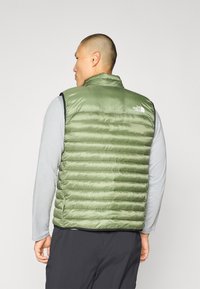 Lichtgroene, gewatteerde puffer vest met een hoge kraag, voorzien van een logo op de bovenrug en zwarte armsgatenrand. Glad, glanzend materiaal.