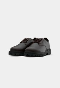 Pair of dark brown leather lace-up shoes with thick black rubber soles, shown side by side on a plain white background.