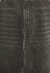 Jeans de ganga pretos com fecho na frente, dois bolsos, textura subtil e ligeiros detalhes de desgaste ao longo das pernas e costuras.