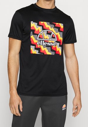 Uomo che indossa una t-shirt nera con grafica a zigzag colorata e logo ellesse, abbinata a pantaloni della tuta ellesse grigio scuro.