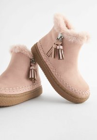 Roze suède enkellaarsjes met een nepbont kraag, decoratieve kwastjes en een getextureerde rubberen zool met zichtbare stiksels.