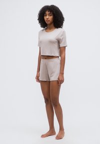 Ensemble crop top et short marron clair en tissu doux. Le haut a des manches courtes et un col rond, tandis que le short est doté d'une taille élastique.