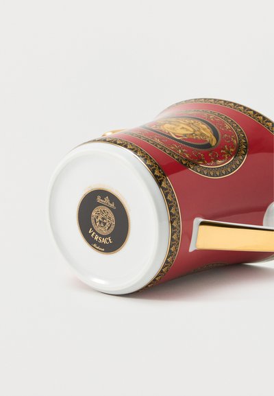 Κόκκινη και χρυσή διακοσμημένη κούπα Versace Medusa που βρίσκεται στο πλάι, δείχνοντας λεπτομερή σχεδίαση Medusa και λαβή με χρυσές λεπτομέρειες.