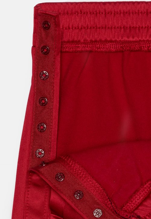 Punane kangasriie, millel on sile tekstuur, elastne vöökoht ja viis kontrastset musta tõmbluku nuppu ühe külje peal.