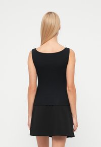 Μαύρο αμ άνικο τοπ με στρογγυλή λαιμόκοψη, φτιαγμένο από λεία ύφη. Εφαρμοστή γραμμή, συνδυασμένη με φούστα σε μαύρο χρώμα με φαρδιά γραμμή.