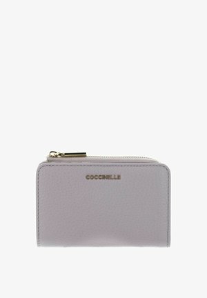 Portefeuille en cuir texturé gris clair avec une fermeture éclair dorée et le nom de la marque Coccinelle embossé en or au centre devant.