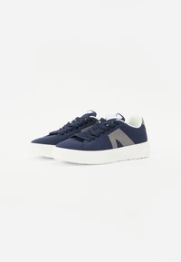 Zapatillas de malla en color navy con suelas de goma blanca, que presentan cordones redondos y un detalle de logo en gris contrastante en el lateral.