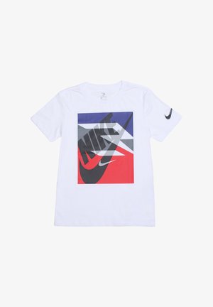 T-shirt en coton blanc avec un grand motif graphique en rouge, bleu et gris, arborant un logo Nike noir et un swoosh sur le devant et la manche.