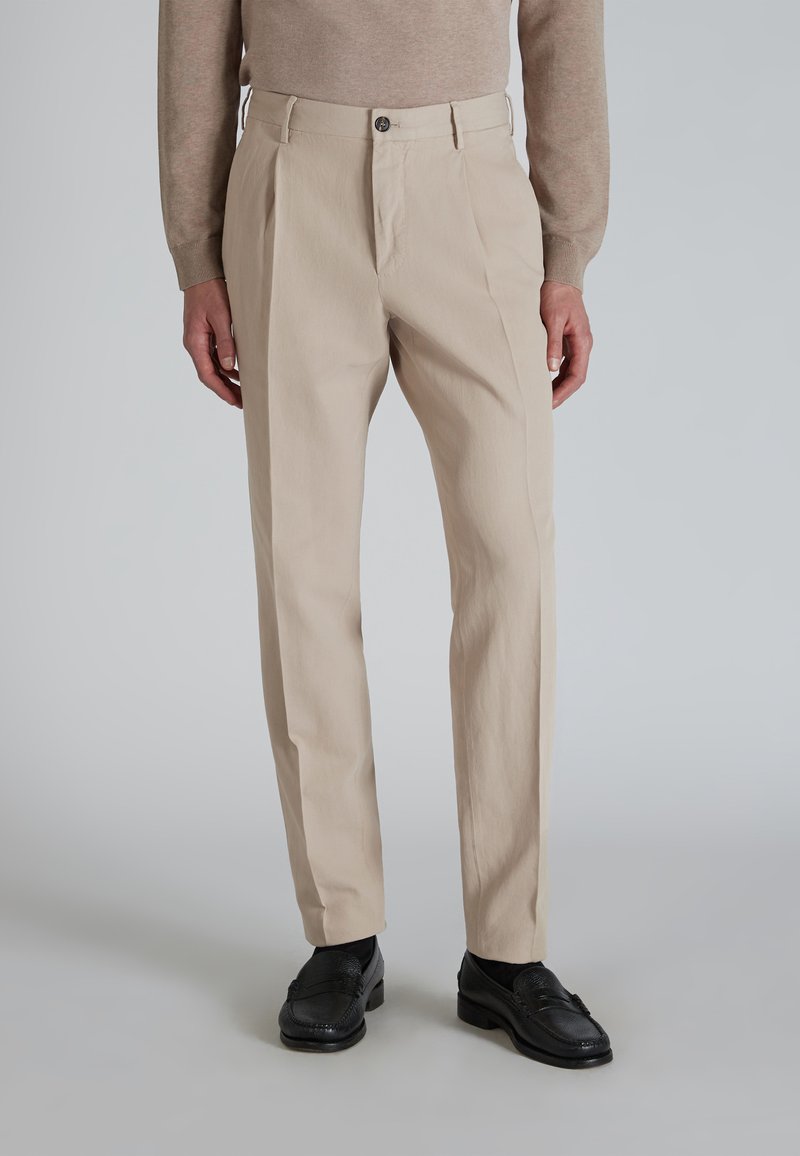 Beżowe spodnie wykonane z lekkiego materiału, z prostym krojem, zapinane na guziki z przodu i z bocznymi kieszeniami. Gładka faktura z minimalnymi detalami.