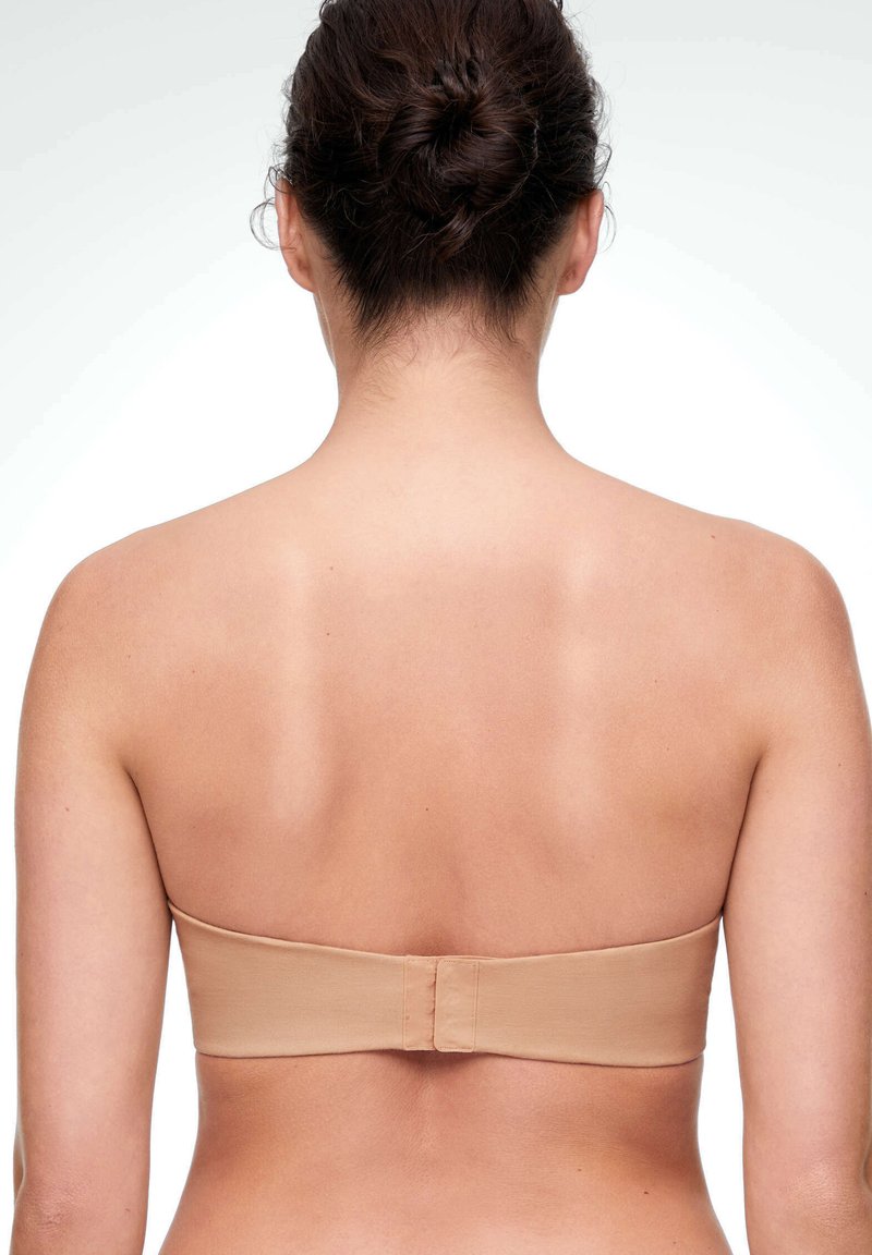 Soutien-gorge beige sans bretelles au toucher lisse, avec une bande ajustable et un système de fermeture par crochets à l'arrière. Design simple et sans ornements.