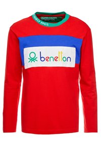 Camisa de manga larga roja con paneles de hombro azules y un logo rectangular blanco con el texto colorido "benetton". Material de algodón con cuello redondo.
