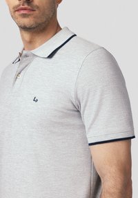 Szara koszulka polo wykonana z fabricu bawełnianego z domieszką, z trzema guzikami, granatowym wykończeniem kołnierzyka oraz haftowanym logo na piersi.