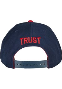 Marineblå stofkasket med rød "TRUST" broderi på bagsiden. Har en plastisk justerbar rem med flere hul til størrelsesjustering.