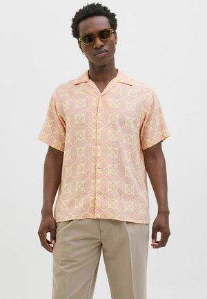 Short-sleeve shirt in pink and yellow with circular pattern. Features a spread collar and button front. Worn with light-colored trousers.
