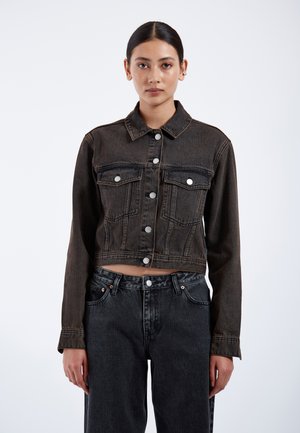 Schwarze Denim-Cropped-Jacke mit Knopfverschluss, zwei Brusttaschen und seitlichen Nahttaschen. Starker Textur mit leichten Stickakzenten.