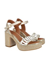 Sandalias de plataforma beige con tacón grueso, que cuentan con detalles a rayas blancas, acentos metálicos y correas de tobillo ajustables. Suela de tejido texturizado.