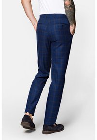 Niebieskie spódnie w kratę, wykonane z tkaniny o gładkiej teksturze, z tylnymi kieszeniami i dopasowanym krojem, połączone z ciemnym obuwiem.