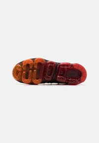 Nike Air Max såle i svart, med flerfargede luftputepodder i oransje og rødt, jevn tekstur og distinkt mønster.