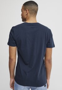 Mørkeblå bomulds t-shirt med korte ærmer, rund hals og en afslappet pasform. Glat tekstur med et enkelt design, uden synlige mønstre eller detaljer.