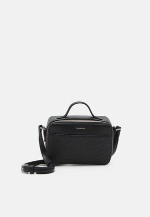 Petit sac bandoulière rectangulaire noir Calvin Klein avec poignée haute, motif logo en relief et bandoulière réglable.