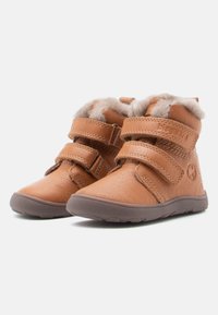 Bottes chevilles en cuir marron avec deux sangles auto-agrippantes, doublure en fourrure douce, semelle en caoutchouc et design à bout rond.