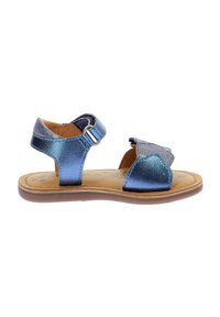 Sanda vestida metálica azul para niños con un diseño de tiras en forma de concha, hebilla ajustable en el tobillo y planta beige. Suela plana con textura ligera.