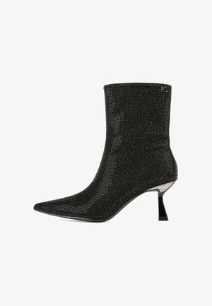 Botas negras hasta el tobillo con una parte superior de punto ajustada, punta afilada y tacón de aguja. Cubiertas de pequeños adornos brillantes que añaden textura.