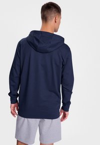Marinblå hoodie med lång ärm, tillverkad av ett slätt tyg. Har en avslappnad passform och en enkel design utan mönster.