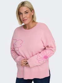 Pink knitted sweater with floral designs on sleeves, ribbed hem, and cuffs. Features a relaxed fit and soft texture. Paired with denim.
