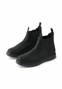 Botas Chelsea negras hechas de material sintético texturizado, con paneles laterales elásticos, lengüetas de tirón y una suela plana de goma.
