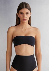 Sort bandeau bikini top parret med højtaljede bottom. Glat, strækbart materiale med et minimalistisk design og ingen synlig hardware.