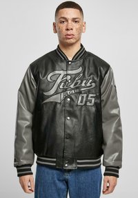 Black leather varsity jacket with gray sleeves, featuring a large graphic print and ribbed collar and cuffs. Buttons and side pockets included.