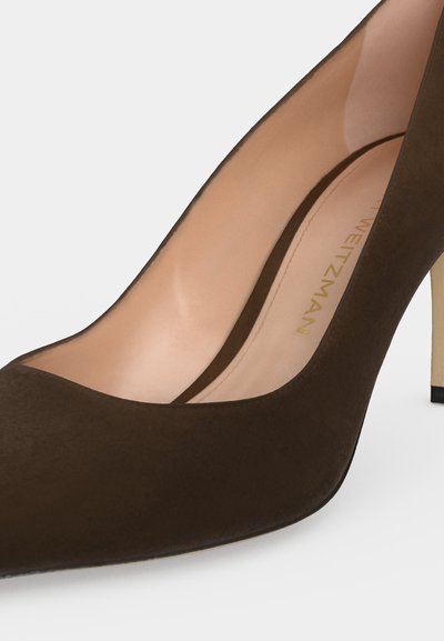 Nahaufnahme eines dunkelbraunen Wildleder-Pumps mit spitzer Schuhspitze und beigem Innenfutter.