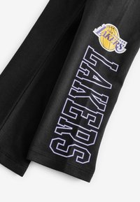 Svart sweatshirt med en lila inramad "LAKERS" text och en färgad logga på övre vänstra sidan. Mjuk bomullsmaterial, design med rund hals.