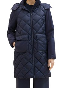 Námořnický prošívaný puffer kabát má zapínání na zip, dvě přední kapsy a odnímatelnou kapuci s patentkami. Středně dlouhý design, hladká textura.