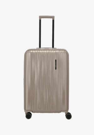 Valise rigide beige avec des rainures verticales, quatre roues pivots et une poignée télescopique déployée vers le haut.