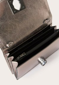 Metallisch silbernes Portemonnaie mit strukturiertem Finish, ausgestattet mit einem Druckverschluss, mehreren Fächern und einer Reißverschlusstasche für sichere Aufbewahrung.