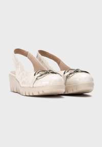 Zapatos de cuña blanco con tira trasera, con un patrón texturizado de cocodrilo, acento metálico y una suela gruesa y estriada para mayor soporte.