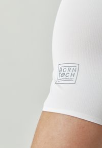 Biele krátke rukávy tričko s rebrovanou textúrou; má šedú nášivku "BORN TECH" na rukáve, ktorá zdôrazňuje názov značky a technológiu.