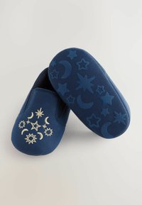 Chaussures slip-on en textile bleu marine avec broderie céleste dorée à l'avant et semelle en caoutchouc décorée de motifs d'étoiles et de lunes.