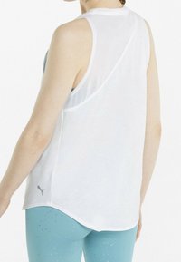 Top atlético sin mangas blanco con un respaldo transparente, dobladillo redondeado y un sutil detalle de logo en el lado inferior, combinado con leggings azules con estampado.