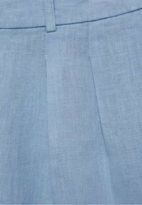 Tela de lino azul claro con un tejido texturizado. Presenta un frente plano y pliegues sutiles, mostrando un diseño suave y transpirable.