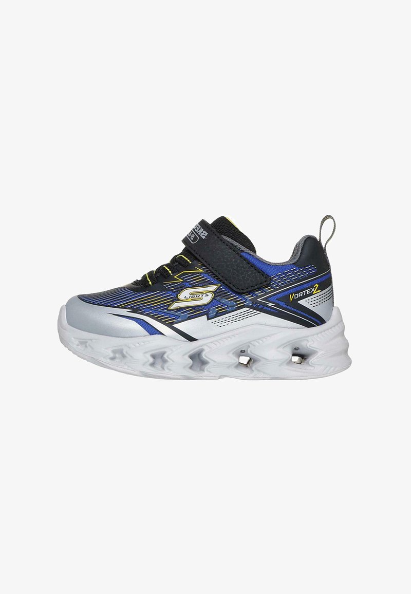 Zapatillas deportivas con un upper sintético en negro, azul y plata, que cuentan con una correa de Velcro, detalles texturizados y una suela blanca con patrón de ondas.