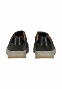 Braune Wildleder-Slipper mit schwarzem Lederakzent an der Ferse, weißer Gummisohle und dezenten Nahtdetails.