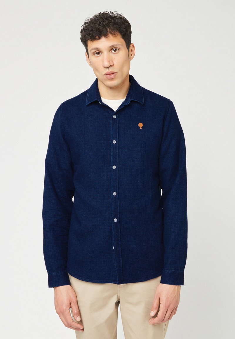 Donkerblauwe button-up shirt van gestructureerde stof, met een klein oranje boomlogo op de borst en een klassiek kraagontwerp.