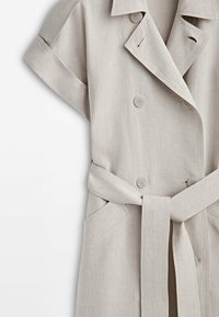 Jasno beżowa sukienka z lnu, zapinana na krótki rękaw, z podwójnymi guzikami, paskiem oraz dwiema przednimi kieszeniami.