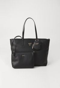 Svart faux skinn toteveske med to stropper, en glidelommer på forsiden og en avtakbar pose. Gullfarget maskinvare fremhever merkevaren.